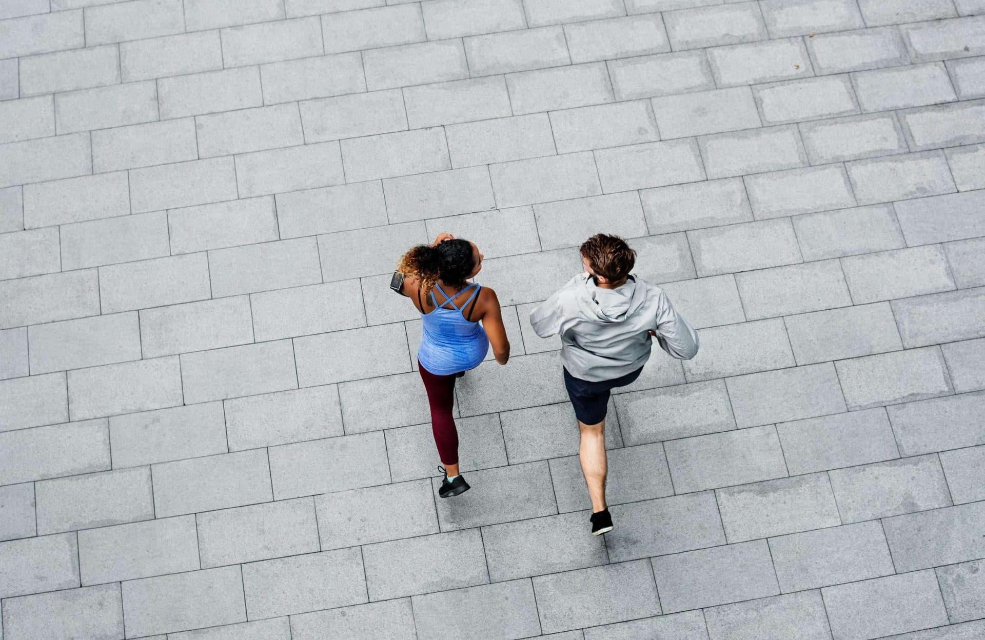 Two runners seen from above on a paved path